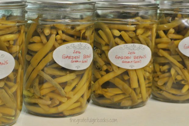 Sealed jars of green beans are labeled before storing in pantry.
