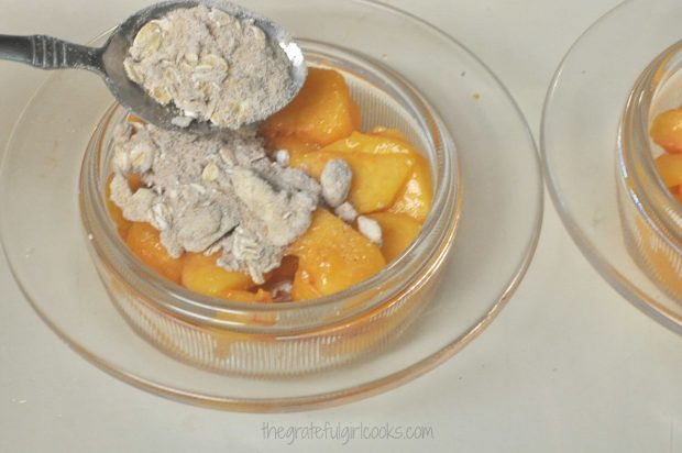 Streuesel topping is placed on top of peaches.