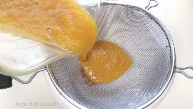 Blended peach coulis is poured through a fine mesh strainer.