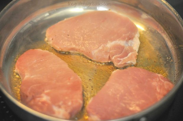 Pork chops are pan-seared in oil until browned on both sides.
