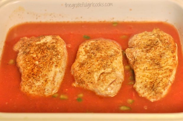 Seared pork chops are placed on top of tomato/rice mixture in baking dish.