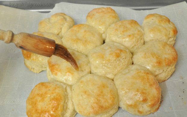 Melted butter being brushed on top of biscuits