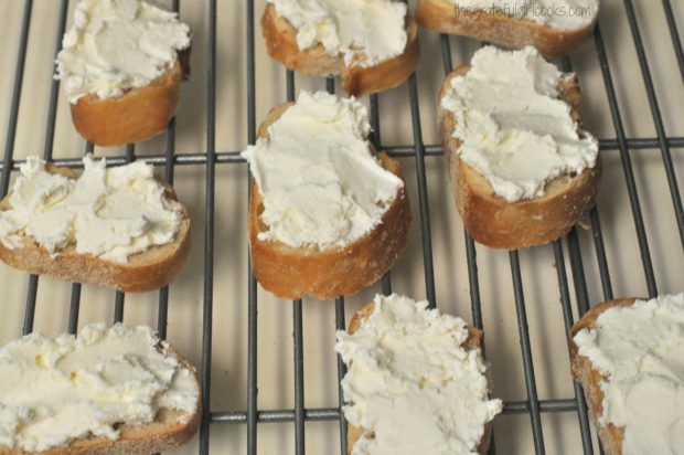 Feta and cream cheese mixture is spread onto the baked crostini slices.