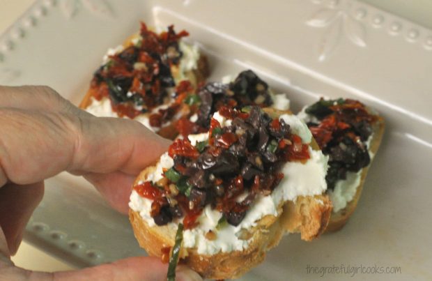 Picking up one of the tomato kalamata olive bruschetta appetizers for a bite!