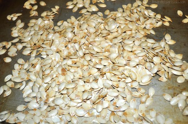 Roast pumpkin seeds are cooked on baking pan in oven for about 25 minutes.