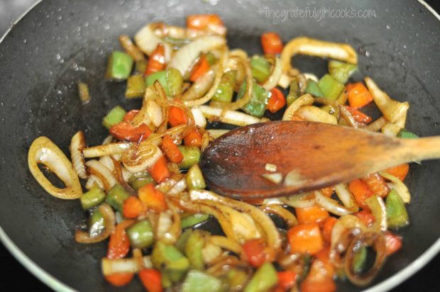 Chopped bell peppers and sliced onions are cooked until golden brown.