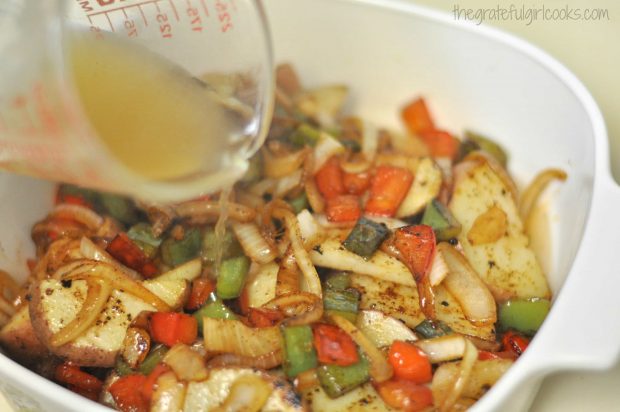 Peppers, onions, and chicken stock are poured over the Italian sausage potato casserole.