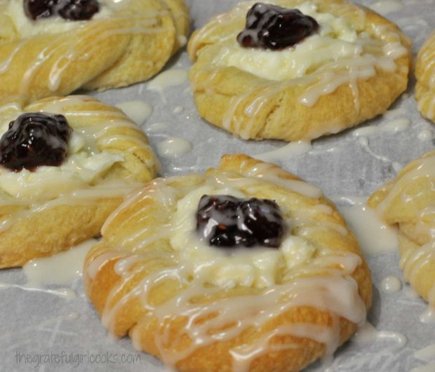 A drizzle of icing is added to each of the raspberry cream cheese danish pastries before serving.