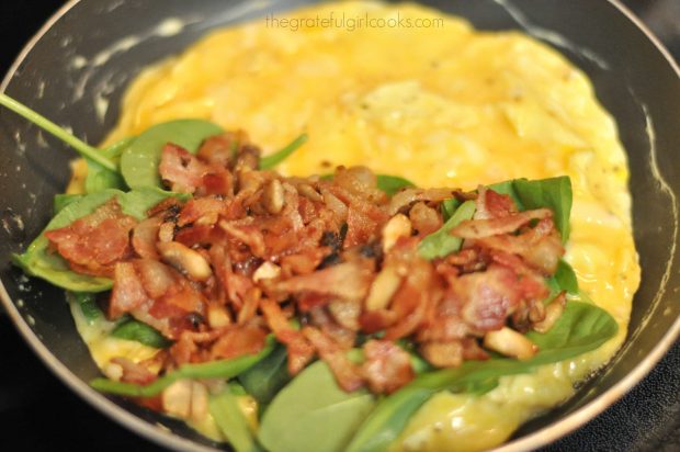 Cooked bacon added to omelette with spinach