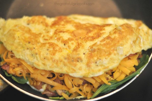 Omelette flipped over halfway over bacon, spinach and cheese