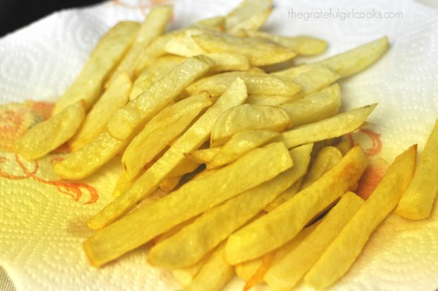 Homemade french fries are placed on paper towels to drain after first frying.