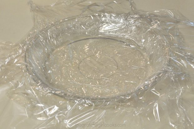 A standard pie dish is completely covered with plastic wrap.