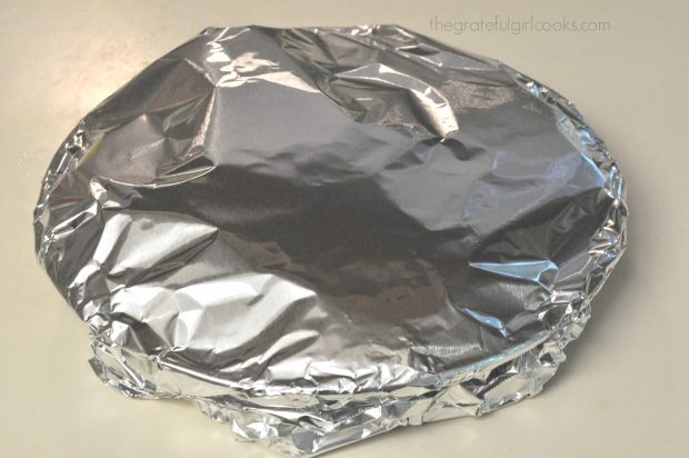 Aluminum foil covers the plastic wrapped pie filling.