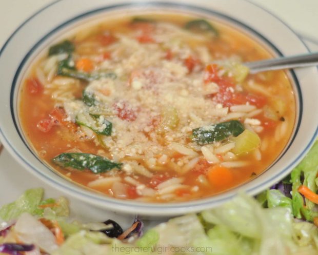 Grated Parmesan cheese is added to Italian orzo spinach soup before serving.