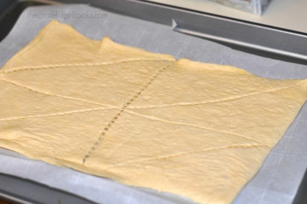 Crescent dough rolled out on parchment paper to make chocolate cream cheese danish.