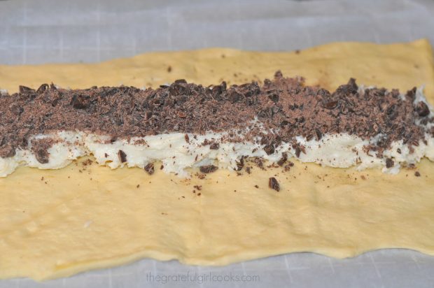 Chopped chocolate sprinkled onto cream cheese filling on dough