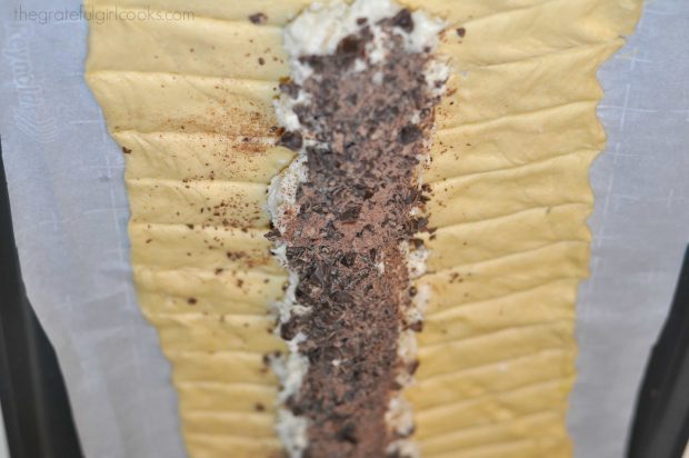 Dough with strips cut on sides, with chocolate and cream cheese in middle