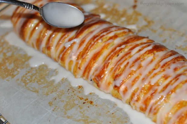 Glaze being spooned over top of baked chocolate cream cheese danish.