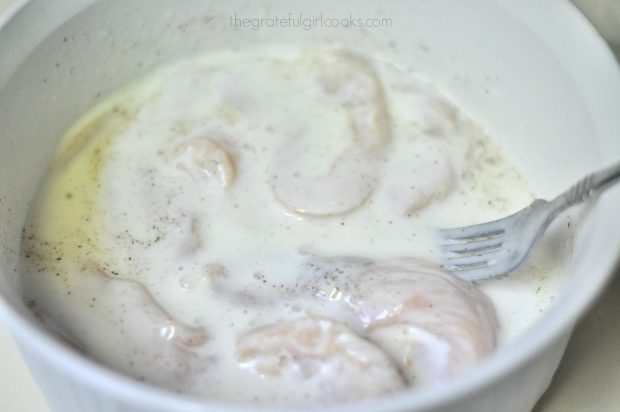 Chicken strips dipped in buttermilk in white bowl