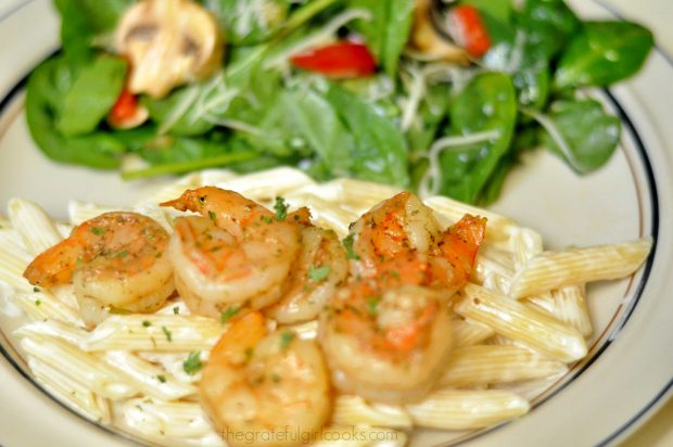 Shrimp Penne Pasta Alfredo is served on plate, with green salad.