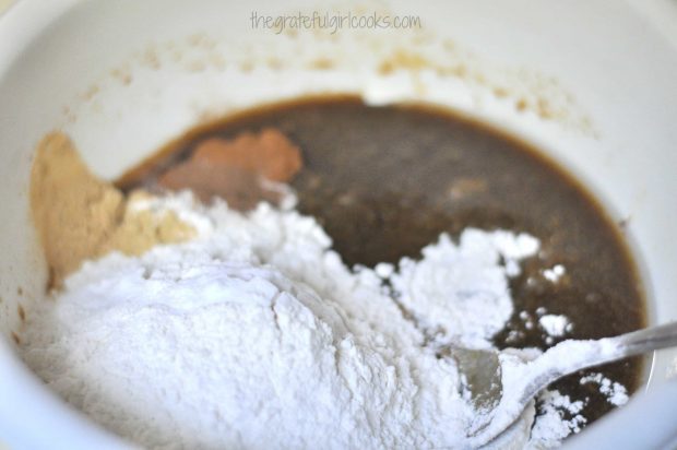 Dry ingredients are added to gingerbread muffin batter in bowl.