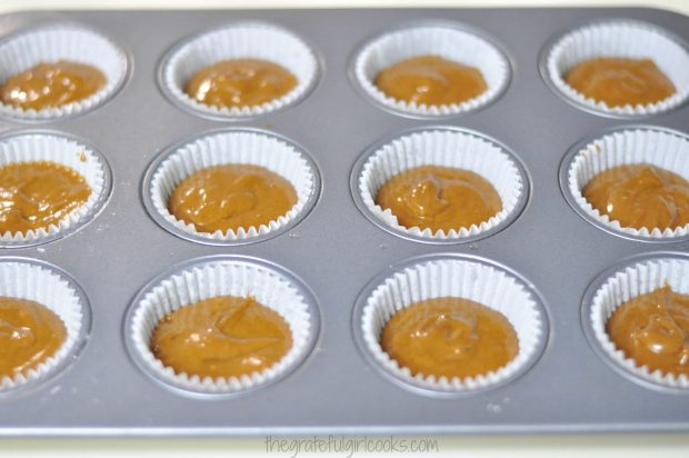 Batter for gingerbread muffins is divided into muffin holders.