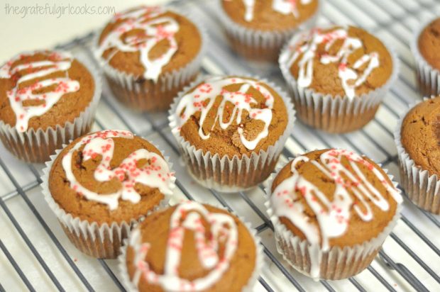Gingerbread muffins are drizzled with powdered sugar icing and red sprinkles.
