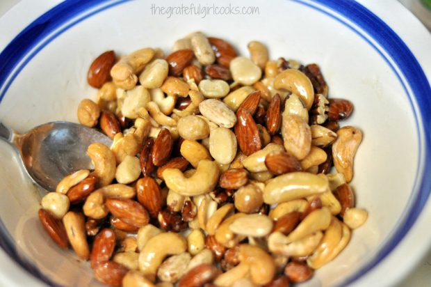 Mixed nuts are coated with melted butter before adding spices.