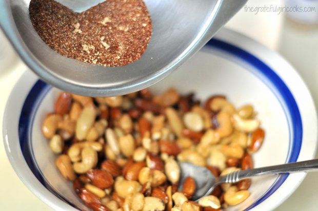 Spice mixture is poured into bowl of butter roasted nuts.