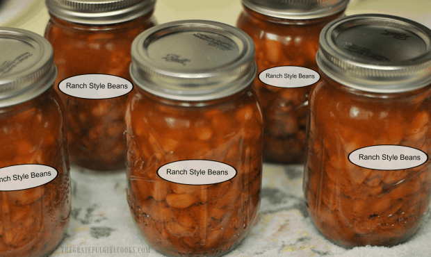 After the canning process is over, the jars of ranch style beans cool on a dish towel.