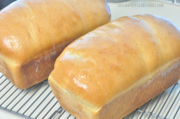 Two loaves of butter brushed homemade bread on wire rack