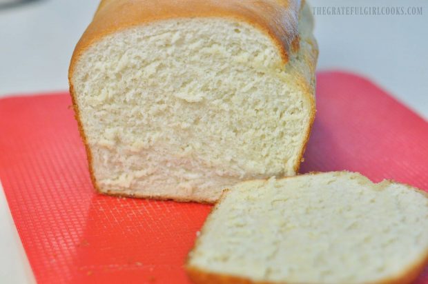 Inside look at loaf of bread with slice laying on red plastic cutting board