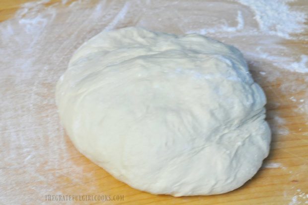 Ball of bread dough on wood cutting board