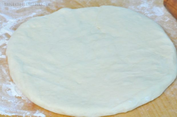 White bread dough rolled out on wood board