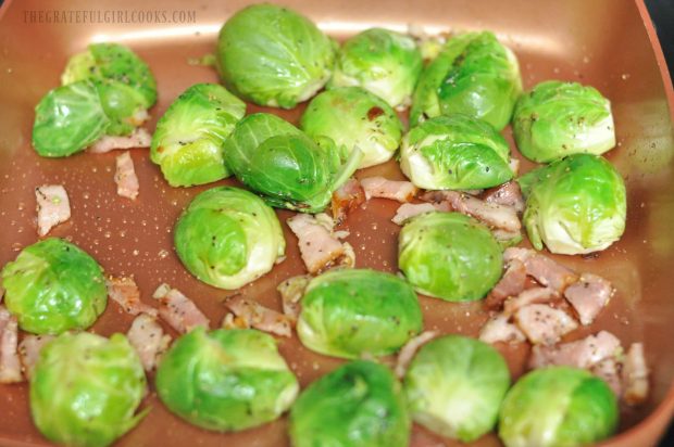 Brussel sprouts and bacon pieces are cooked in bacon drippings in skillet.