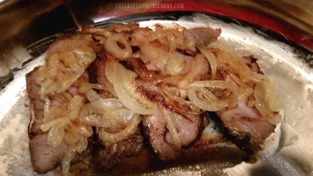 Caramelized onion slices are added to the pork tenderloin sandwich.