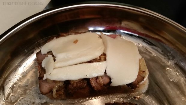 Mozzarella cheese slices are placed on top of the caramelized onions.