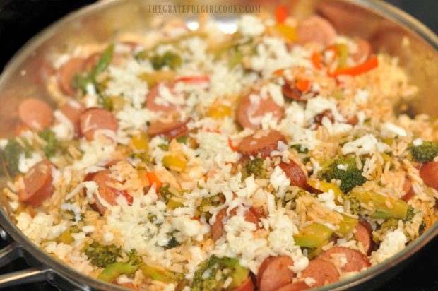 Shredded mozzarella cheese is added to top of smoked sausage veggie rice skillet.
