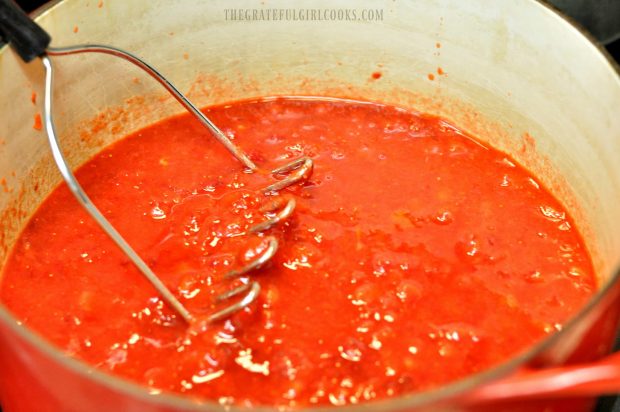 Mashing strawberries in large saucepan