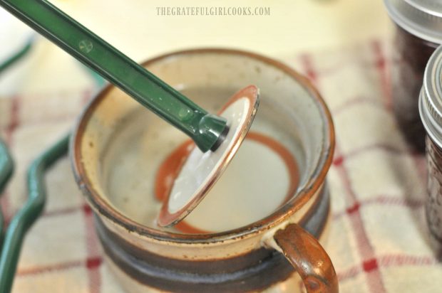 Canning jar flat lid lifted out of hot water