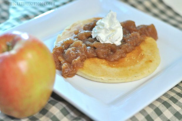 Chunky Crock Pot Apples are served on top of pancakes, with a dollop of whipped cream.