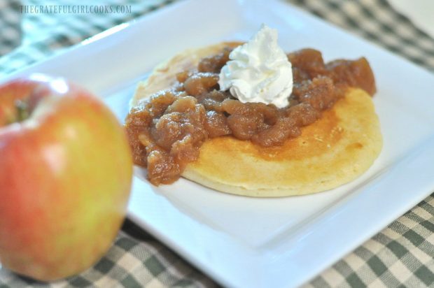 Chunky Crock Pot Apples are served on top of pancakes, with a dollop of whipped cream.