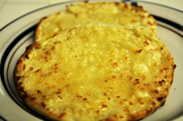 Close up photo of a toasted, fork-split English muffin, with melted butter.