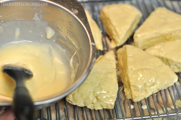 Lemon glaze added to scones on wire rack with a pastry brush