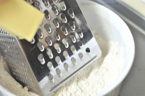 Frozen butter is grated into dry ingredients in bowl