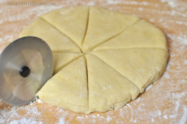 Lemon cream scone dough is cut into 8 wedges with pizza cutter