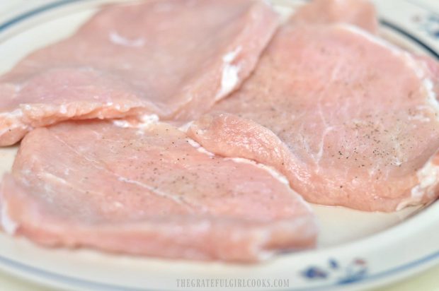 Raw pork cutlets on plate before pan-searing.