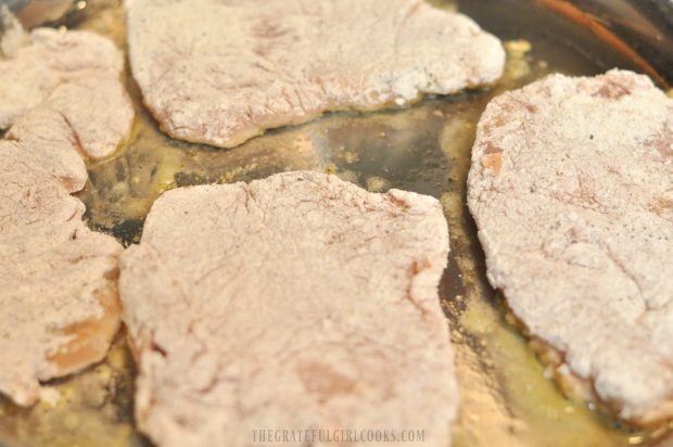 Pork cutlets are seared in large skillet with oil.