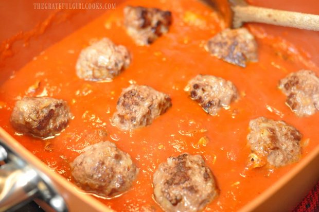 Meatballs are placed in spaghetti sauce to finish cooking.