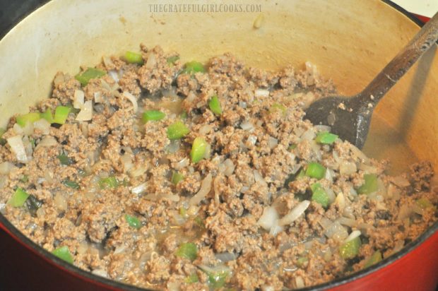 Ground beef, onions, and bell pepper are cooked in pan.